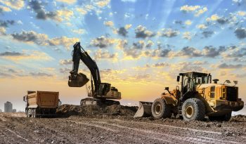 Excavators working on construction site at sunset